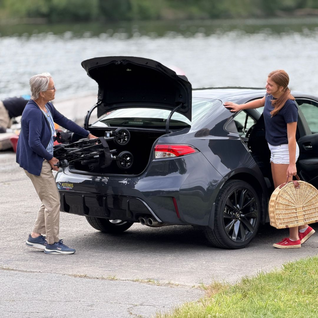 A folded Cricket power wheelchair being loaded into a vehicle.